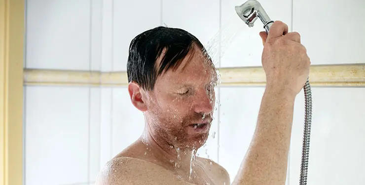En man duschar och spolar vatten i ansiktet
