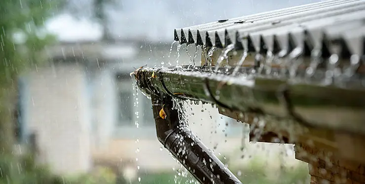 En hängränna på ett tak där regnet öser ner och svämmar över rännan.