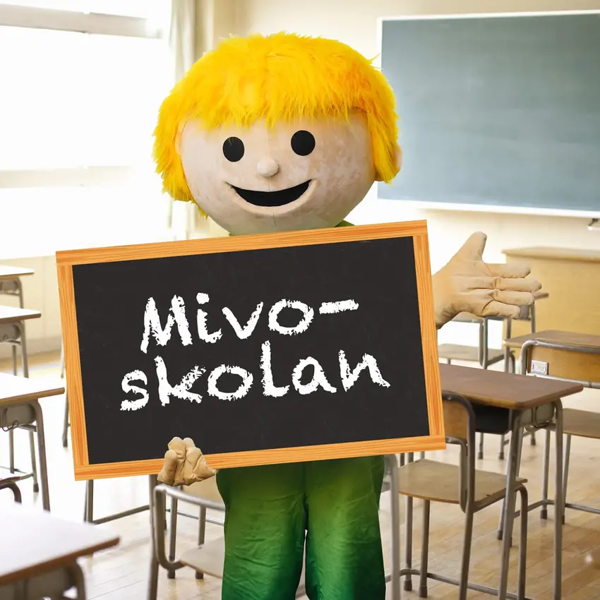 Den grafiska figuren Mivo står i ett klassrum och håller i en svarta tavlan med texten "Mivo-skolan"